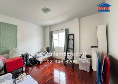 Bedroom with wooden flooring and various items stored