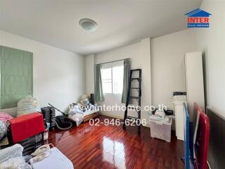 Bedroom with wooden flooring and various items stored