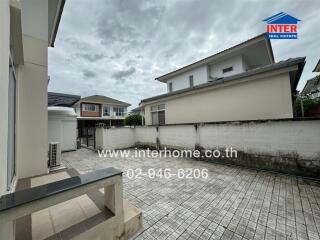 Outdoor backyard space with tiled flooring and adjacent buildings.