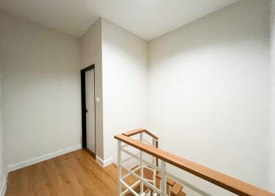A minimalistic staircase landing with wooden handrails and white walls