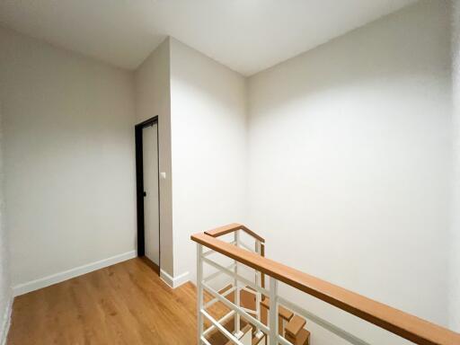 A minimalistic staircase landing with wooden handrails and white walls