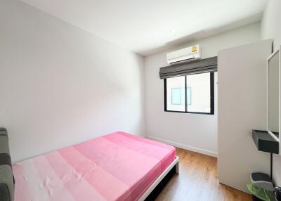 A bright bedroom with a pink bed, window, and air conditioning unit