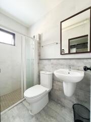 Modern bathroom with glass shower, toilet, and sink