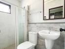 Modern bathroom with glass shower, toilet, and sink