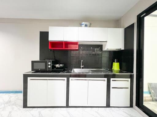 Modern kitchen with white and black cabinetry, stainless steel sink, and microwave