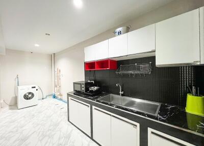 Modern kitchen with white cabinets, black countertop, and washing machine