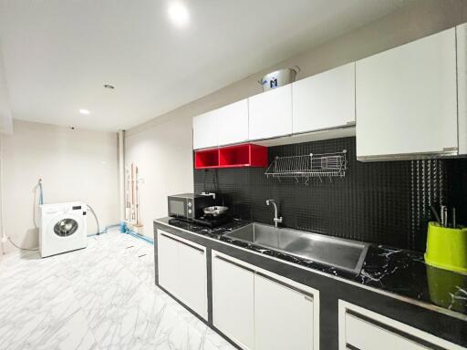 Modern kitchen with white cabinets, black countertop, and washing machine