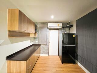 Modern kitchen with wooden cabinets, black countertops, and enclosed appliances