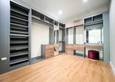Large walk-in closet with shelves, drawers, and dressing area