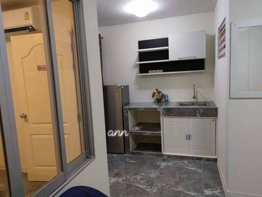 Minimalist kitchen with marble floor, sink, cabinetry, and refrigerator