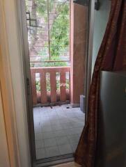 View of a balcony with a sliding door, railing, and tree outside