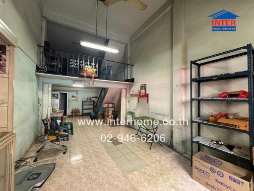 Interior view of a building with tiled floor, mezzanine, and shelving.