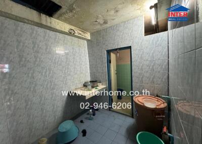 Bathroom with tiles, bucket, and wash basin