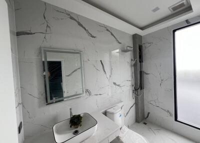 Modern bathroom with marble tiles, wall-mounted sink, and shower