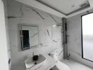 Modern bathroom with marble tiles, wall-mounted sink, and shower