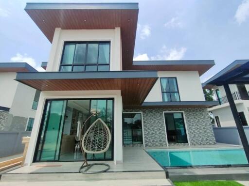 Modern two-story house with large windows, a swimming pool, and a hanging chair