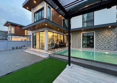 Modern two-story house with large windows, swimming pool, and outdoor seating area