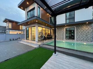 Modern two-story house with large windows, swimming pool, and outdoor seating area