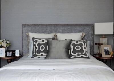 Modern bedroom with decorative pillows and a gray upholstered headboard.
