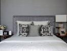 Modern bedroom with decorative pillows and a gray upholstered headboard.