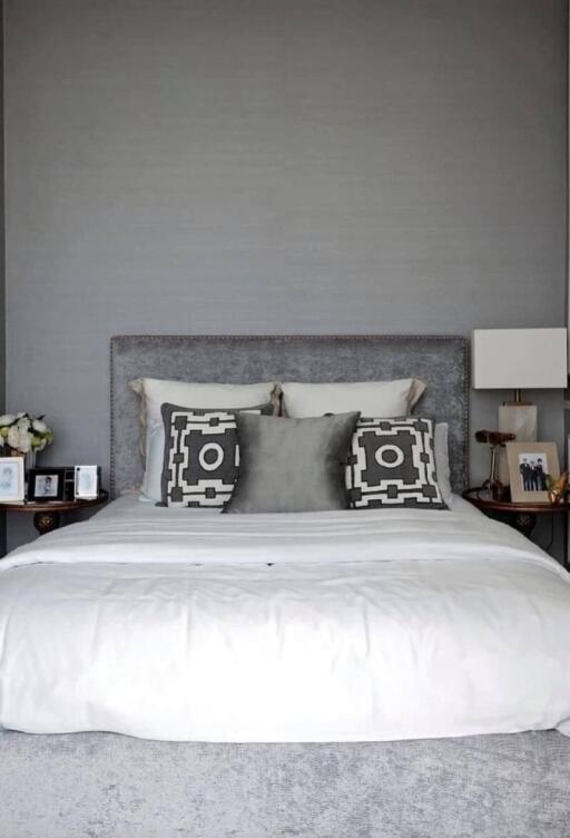 Modern bedroom with decorative pillows and a gray upholstered headboard.