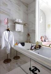 Modern bathroom with marble walls, featuring a bathtub, towel rack, and indoor plants