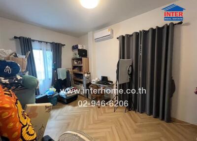 Bedroom with light-colored wooden floor, curtains, bookshelf, and air conditioning unit