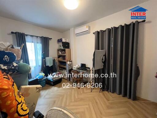 Bedroom with light-colored wooden floor, curtains, bookshelf, and air conditioning unit