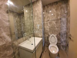 Modern bathroom with marble tiles, glass shower, and white fixtures