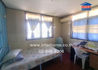 Bedroom with bed, study desk, chairs, and windows with curtains