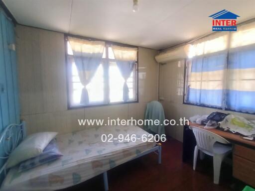 Bedroom with bed, study desk, chairs, and windows with curtains