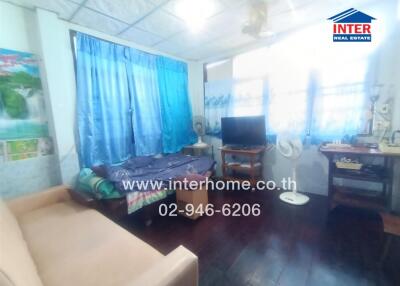 Bedroom with bed, couch, TV, and windows with blue curtains