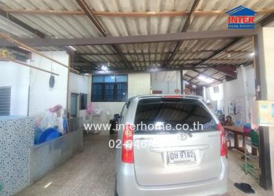 Indoor garage with a car, washing area, and some personal belongings.