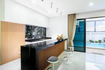 Modern kitchen with countertop and bar stools, adjacent to a pool area