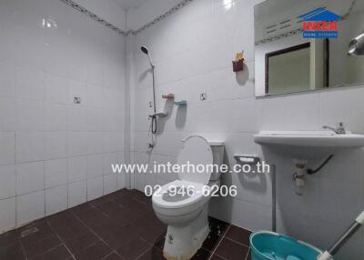 Bathroom with white tiles, toilet, sink, mirror, and shower.