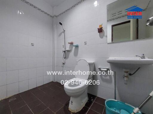 Bathroom with white tiles, toilet, sink, mirror, and shower.