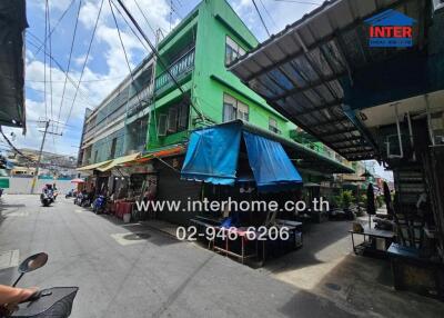 Street view of a building with green facade and shopfronts