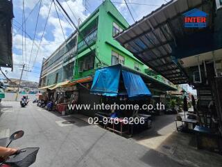 Street view of a building with green facade and shopfronts