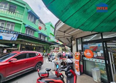 Street view with storefronts, cars, and motorcycles