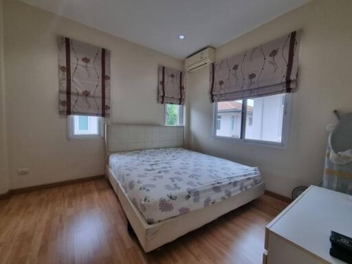 A cozy bedroom with a bed, wooden flooring, and large windows.