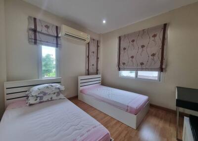 Bedroom with two single beds, air conditioning, wooden floor, and window blinds