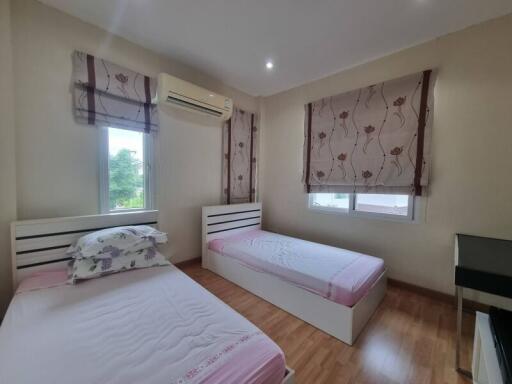 Bedroom with two single beds, air conditioning, wooden floor, and window blinds