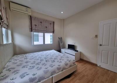 Spacious bedroom with bed, windows, air conditioning, and a small desk with a TV