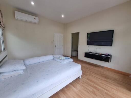 Spacious bedroom with a large bed, wall-mounted TV, and wooden flooring