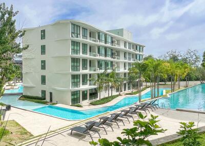Exterior view of a modern residential apartment complex with swimming pools and lounge area