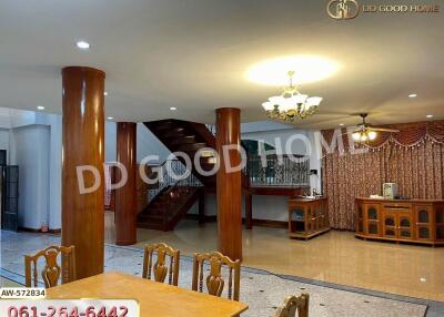 Spacious living and dining area with wooden pillars and a stairway