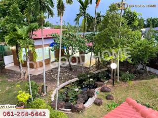 A scenic view of a property with a garden, trees, and a pond