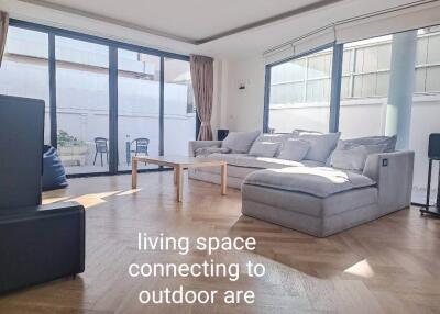 Spacious living room connecting to outdoor area with large windows and modern furniture.