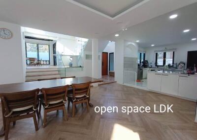 Open space LDK with wooden dining table, chairs, modern kitchen, and staircase