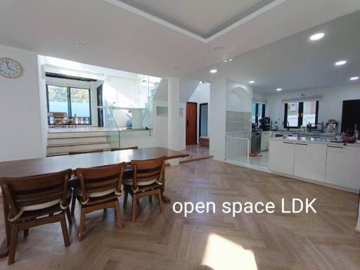 Open space LDK with wooden dining table, chairs, modern kitchen, and staircase